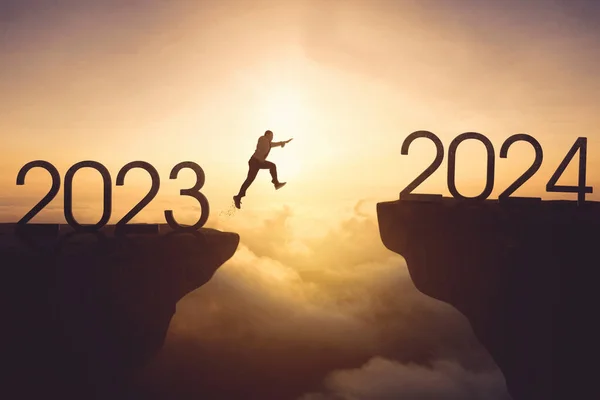 stock image New year concept. Businessman jumping gap on the cliff from number 2023 to number 2024