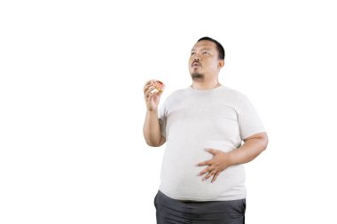 Overweight fat Asian man holding a doughnut while thinking of something isolated over white clipart