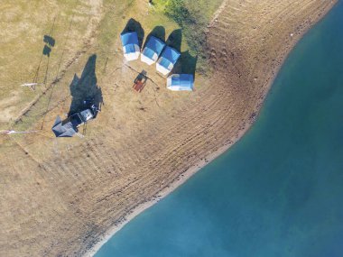 Göl kenarındaki kaygısız turist kamp alanının üzerinde uçuyor.