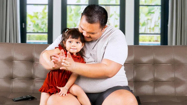 Overweight Asian man clapping hand at home with his little cute girl