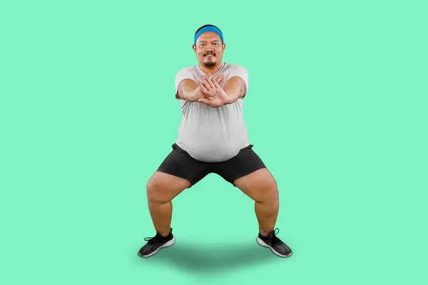 Ασιατικός Υπέρβαρος Τύπος Τεντώνοντας Άσκηση Γυμναστική Απομονώνονται Πράσινο Φόντο — Φωτογραφία Αρχείου