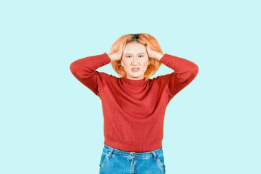 Asyalı güzel bir kadın stresli, kafası karışık ve baş ağrısı açık mavi arka planda izole edilmiş.