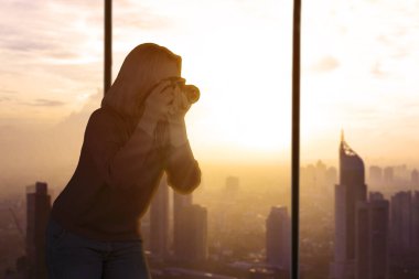 Gün batımında şehir manzarasının fotoğraflarını çeken kadın fotoğrafçı silueti.