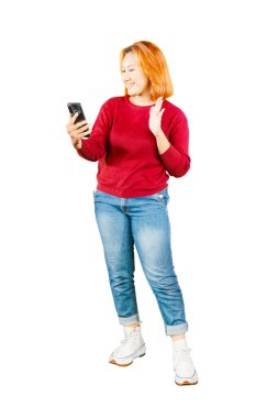 Güzel Asyalı bir kadının beyaz arka planda izole edilmiş cep telefonuyla selfie çekerken gülüp barış işareti yaptığı görüntüsü