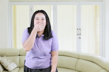 Mor gömlek giyen mutlu dışa dönük genç şişman kız ellerini ağzını kapatarak mutluluğunu ifade ediyor.