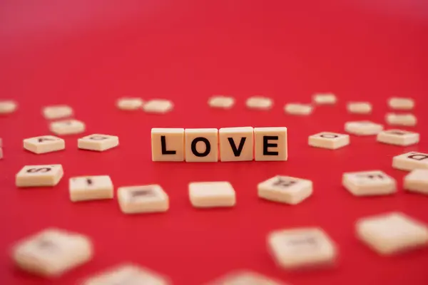 The word LOVE with wooden letter tiles isolated on red background
