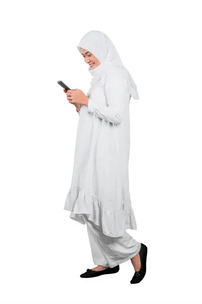 ホワイトバックで隔離された携帯電話とヒジャブで幸せな若いアジアのイスラム教徒の女性 — ストック写真