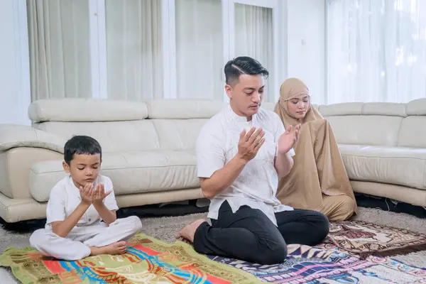 Junge Muslimische Familie Betet Gemeinsam Heimischen Wohnzimmer lizenzfreie Stockbilder