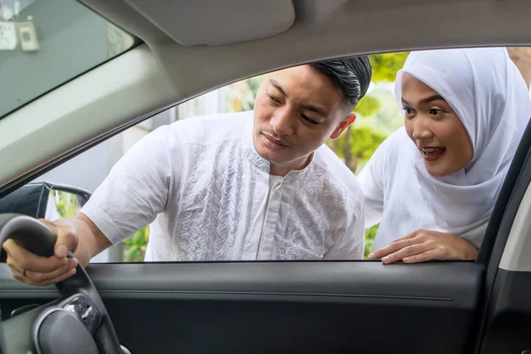 一对快乐的穆斯林夫妇在车展上看汽车内部 图库图片