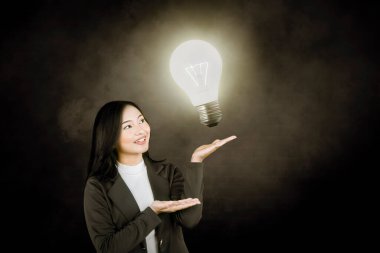 İş kadını Karanlık Arkaplanda Parlayan Ampul Fikrini Sunar