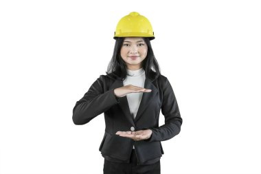 Korumayı temsil eden el hareketleriyle sarı sapkalı kadın mühendis.