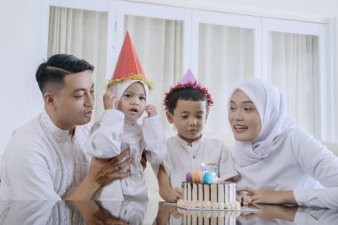 Muslim Family Celebrating a Birthday with Cake and Candles at Home clipart