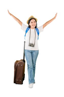 Heyecanlı, kolları havada, bavul ve kamera taşıyan genç bir bayan gezgin.