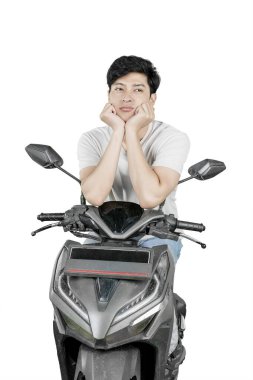 Siyah motosiklette oturan genç adam... Beyaz arka planda izole edilmiş elleri yüzünden sıkılmış görünüyor.