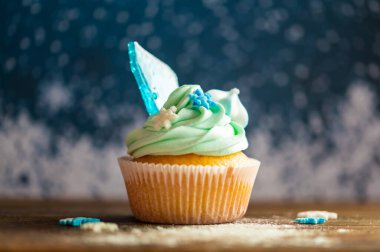 Ahşap masaya konulmuş ev yapımı mavi renkli kek. Kış ve Noel teması, kremalı kar taneleri ve mavi buz. Taze ve ev yapımı tatlı.