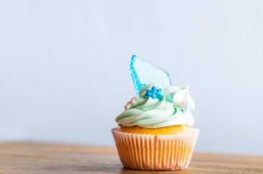 Ahşap masaya konulmuş ev yapımı mavi renkli kek. Kış ve Noel teması, kremalı kar taneleri ve mavi buz. Taze ve ev yapımı tatlı.