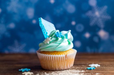 Ahşap masaya konulmuş ev yapımı mavi renkli kek. Kış ve Noel teması, kremalı kar taneleri ve mavi buz. Taze ve ev yapımı tatlı.