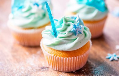 Ahşap masaya konulmuş ev yapımı mavi renkli kek. Kış ve Noel teması, kremalı kar taneleri ve mavi buz. Taze ve ev yapımı tatlı.