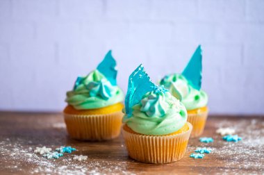 Ahşap masaya konulmuş ev yapımı mavi renkli kek. Kış ve Noel teması, kremalı kar taneleri ve mavi buz. Taze ve ev yapımı tatlı.