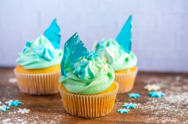 Ahşap masaya konulmuş ev yapımı mavi renkli kek. Kış ve Noel teması, kremalı kar taneleri ve mavi buz. Taze ve ev yapımı tatlı.