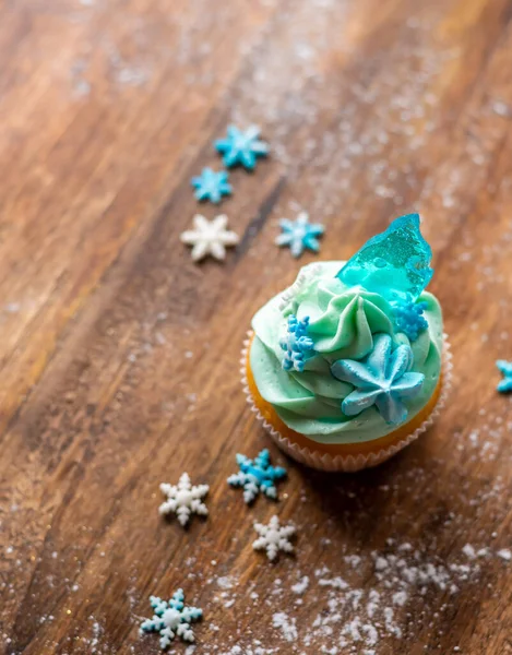 自制的蓝色纸杯蛋糕放在木制桌子上 冬天和圣诞节的主题 雪片在奶油和蓝色冰块上 新鲜和家庭烘焙甜 — 图库照片