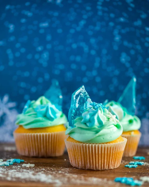 自制的蓝色纸杯蛋糕放在木制桌子上 冬天和圣诞节的主题 雪片在奶油和蓝色冰块上 新鲜和家庭烘焙甜 — 图库照片