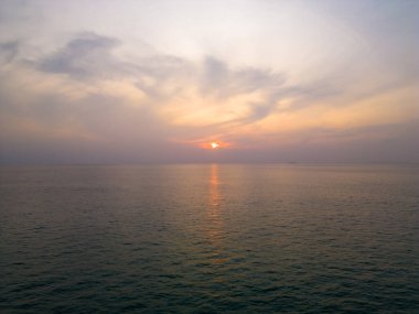 Deniz suyunda gün batımı. Yumuşak sıcak renkler ve yumuşak bulutlar.