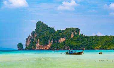 Tayland 'daki Ko Phi Adaları' ndaki kireçtaşından kaya ve teknelerle kıyı şeridi manzarası. Egzotik tropikal tatil kavramı ve cennetteki güzel doğa.