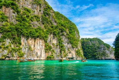 Tayland 'daki Ko Phi Phi adalarındaki Pi Leh lagününün (Yeşil Göl olarak da bilinir) manzarası. Tipik uzun kuyruklu teknenin görüntüsü. Tipik Tayland tropik cennet resmi. Kireç taşı kaya ve turkuaz su.