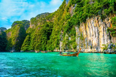 Tayland 'daki Ko Phi Phi adalarındaki Pi Leh lagününün (Yeşil Göl olarak da bilinir) manzarası. Tipik uzun kuyruklu teknenin görüntüsü. Tipik Tayland tropik cennet resmi. Kireç taşı kaya ve turkuaz su.