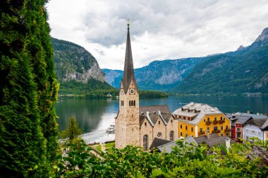 Hallstatt şehrinin ünlü panoraması. Hallstatter yakınlarında tipik bir kilise var. Gökyüzünde dramatik bulutlar. Avusturya 'nın ünlü turizm beldesi.