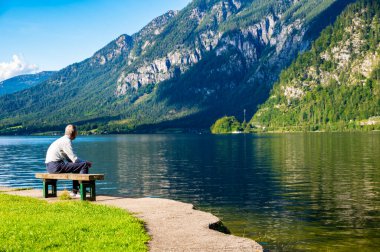 Tanımlanamayan yaşlı adamlar Avusturya Alpleri 'nde göl kenarında bankta oturuyorlar. Rahatlama ve meditasyon kavramı doğaya yakın. Hallstatt Şehri, Avusturya.