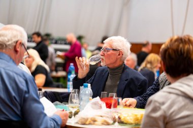 Hrusovany u Brna, Çek Cumhuriyeti - 17.2.2024: Şarap arıtma ve şarap tatma etkinliği. Bardaktan içen insanların görüntüsü. Güney Moravya bölgesi, Palava tepeleri yakınlarındaki şarap diyarı..