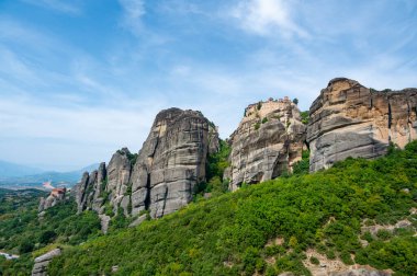 Monastery Meteora Greece. Stunning summer panoramic landscape. View at mountains and green forest against epic blue sky with clouds. UNESCO heritage list object. clipart