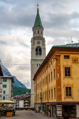 Cortina d 'Ampezzo' nun kalbindeki ikonik kilise kulesinin manzarası. Kulenin mimari güzelliği, çevre Alp manzarasının arka planında dimdik ayakta duruyor.