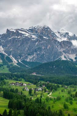 Cortina d 'Ampezzo kasabasının panoramik bir görüntüsü, Dolomitlerin kalbine yerleşmiş. Arka planda muhteşem dağlar yükselir, büyüleyici bir doğal zemin sunar..