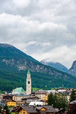 Cortina d 'Ampezzo kasabasının panoramik bir görüntüsü, Dolomitlerin kalbine yerleşmiş. Arka planda muhteşem dağlar yükselir, büyüleyici bir doğal zemin sunar..