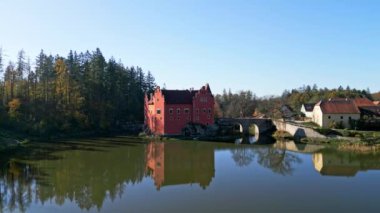 Cervena Lhota Kalesi 'nin (Red Chateau, Schloss Rot) panoramik drone görüntüsü, aşağıdaki göletteki kalelerin yansımasını gösterir. Sonbahar renkli ormanlarla çevrili