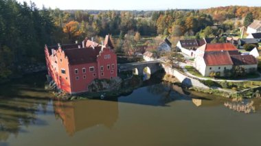Cervena Lhota Kalesi 'nin (Red Chateau, Schloss Rot) panoramik drone görüntüsü, aşağıdaki göletteki kalelerin yansımasını gösterir. Sonbahar renkli ormanlarla çevrili