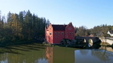 Cervena Lhota Kalesi 'nin (Red Chateau, Schloss Rot) panoramik drone görüntüsü, aşağıdaki göletteki kalelerin yansımasını gösterir. Sonbahar renkli ormanlarla çevrili