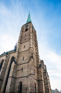 Çek Cumhuriyeti, Plzen 'deki St. Bartholomew Katedrali' nin bir fotoğrafı. Bu Gotik katedrali ikonik kulesi gururla duruyor, tarihi binalarla çevrili, çarpıcı bir manzara sunuyor.