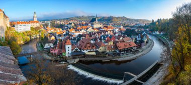 Cesky Krumlov 'un panoramik görüntüsü, Vltava Nehri ile çevrili UNESCO listesindeki tarihi merkezi gösteriyor. Güneşli bir sonbahar günü kasabanın cazibesini vurgular.