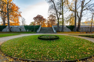 Cesky Krumlov 'da bir parkta, günbatımında ele geçirilen eski kale merdivenleri. Batan güneşin sıcacık parıltısı, tarihi adımların üzerine büyülü bir ışık saçıyor. Huzur parkına cazibe katıyor.