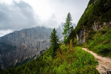 Dolomitler 'deki dağ patikaları (Dolomiti, Dolomiten), İtalya, Lago Sorapis' e çıkar. Yol kayalık yamaçlar boyunca esiyor, vadilerin, ormanların ve tepelerin çarpıcı manzarasıyla.