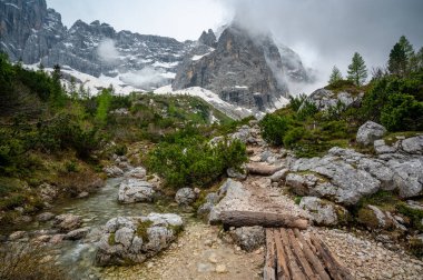 Dolomiti (Dolomiti, Dolomiten), İtalya 'da Lago Sorapis yakınlarında Rocky yürüyüş yolu. Yol, arka planda büyük kayalar ve zirvelerle küçük bir dağ deresinin yanında uzanır.