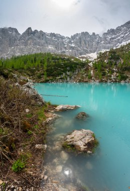 Panoramic view of Lago Sorapis in the Dolomites (Dolomiti, Dolomiten), Italy. The turquoise lake is surrounded by towering cliffs and mountains, a popular spot for hikers and nature lovers clipart