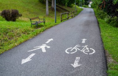 Bisikletçiler ve aylaklar için açık sembollerle işaretlenmiş yaya geçitli asfalt bisiklet yolu manzarası. İkisi için de iyi tasarlanmış bir yol. Güvenli ve kolay bir yolculuk.
