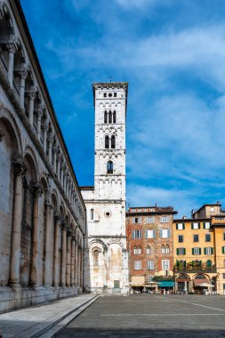 Lucca İtalya 'nın tarihi merkezinde, Chiesa di San Michele' in panoramik manzarası güneşli bir yaz gününde açık mavi gökyüzü ve antik mimaride sıcak bir ışık