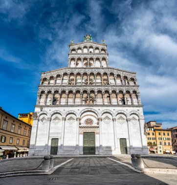 Lucca İtalya 'nın tarihi merkezinde, Chiesa di San Michele' in panoramik manzarası güneşli bir yaz gününde açık mavi gökyüzü ve antik mimaride sıcak bir ışık