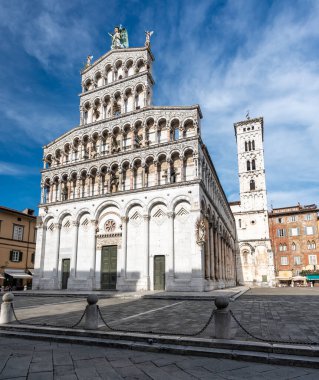 Lucca İtalya 'nın tarihi merkezinde, Chiesa di San Michele' in panoramik manzarası güneşli bir yaz gününde açık mavi gökyüzü ve antik mimaride sıcak bir ışık